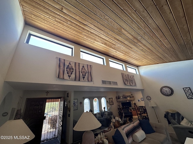 living room with a high ceiling, wooden ceiling, a fireplace, and visible vents