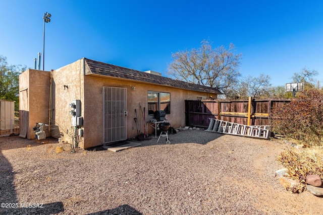 rear view of house with a patio, fence, roof with shingles, and stucco siding