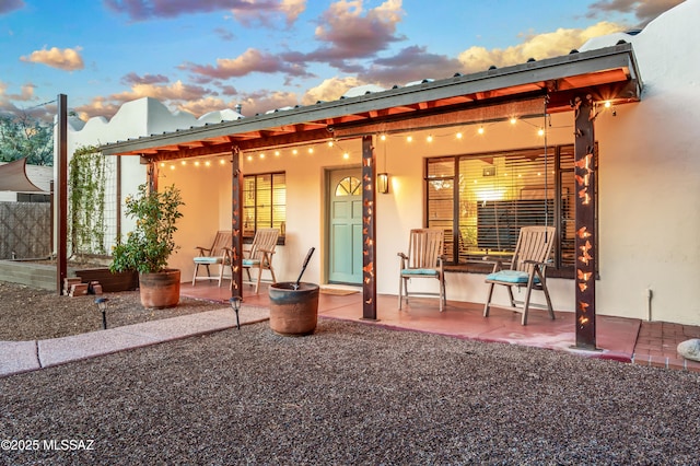 back of house at dusk with a patio area and stucco siding