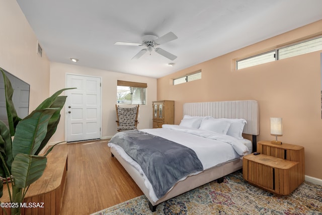 bedroom with visible vents, baseboards, wood finished floors, and a ceiling fan