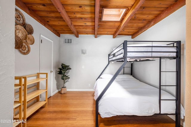 bedroom with wood finished floors, visible vents, beam ceiling, a skylight, and wooden ceiling