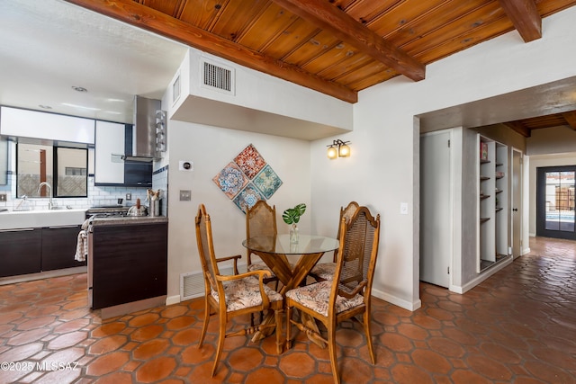 dining area with baseboards, visible vents, beam ceiling, and wood ceiling