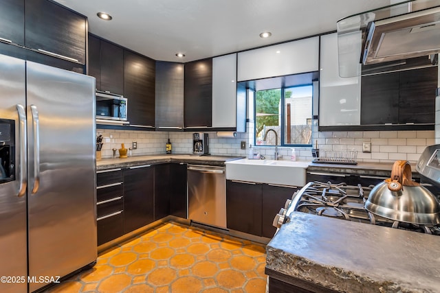 kitchen with modern cabinets, a sink, backsplash, stainless steel appliances, and dark brown cabinetry
