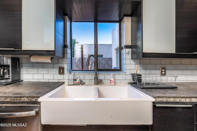 kitchen with a sink, decorative backsplash, dark countertops, and dishwasher