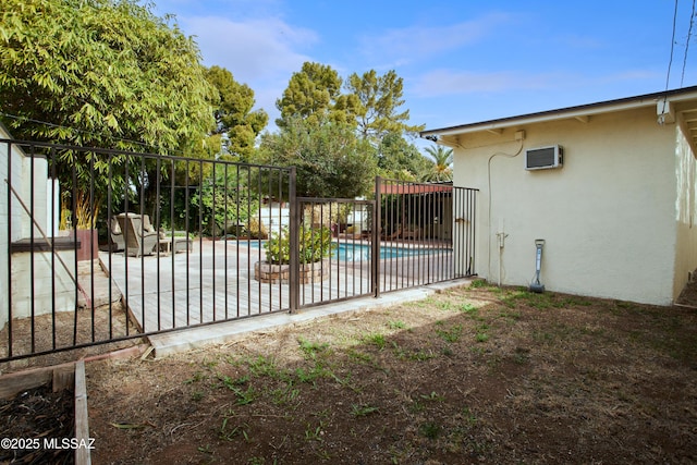 view of gate featuring a patio area, a fenced in pool, a wall mounted air conditioner, and fence