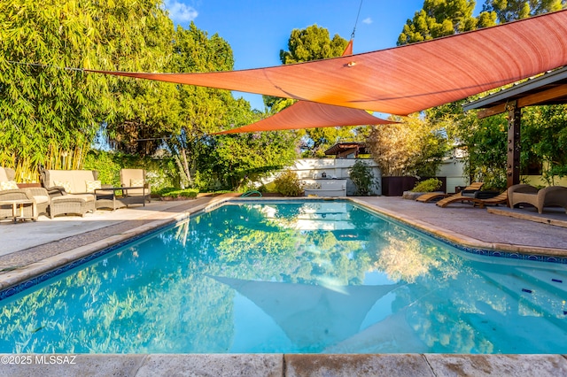 outdoor pool featuring outdoor lounge area, a patio, and a fenced backyard