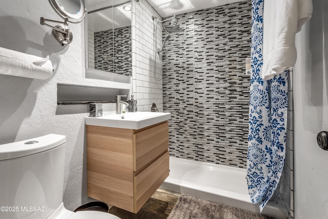 bathroom with a shower stall, toilet, vanity, and a textured wall