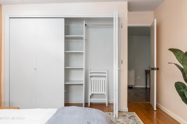 bedroom with wood finished floors, a closet, and baseboards