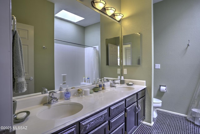 bathroom with a skylight, vanity, tile patterned floors, and toilet