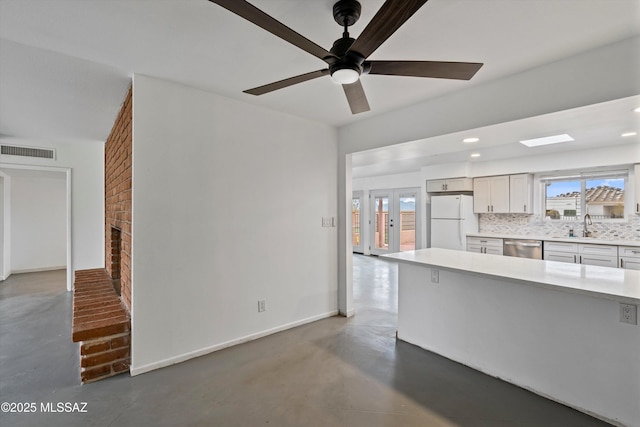 kitchen with dishwasher, sink, backsplash, white fridge, and a brick fireplace