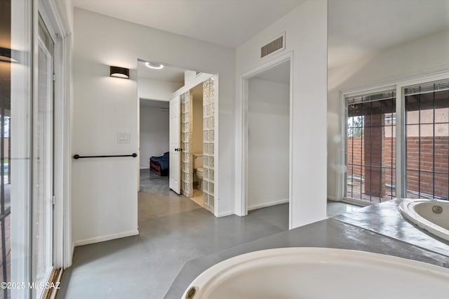 bathroom with a tub and concrete floors