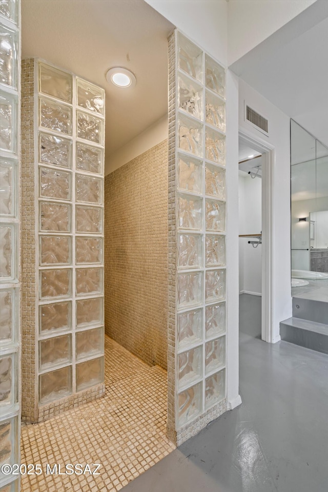 bathroom with concrete flooring and tiled shower