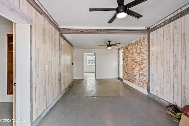 spare room featuring wooden walls, ceiling fan, and brick wall