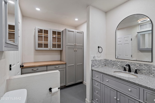 bathroom with vanity, toilet, decorative backsplash, and concrete floors