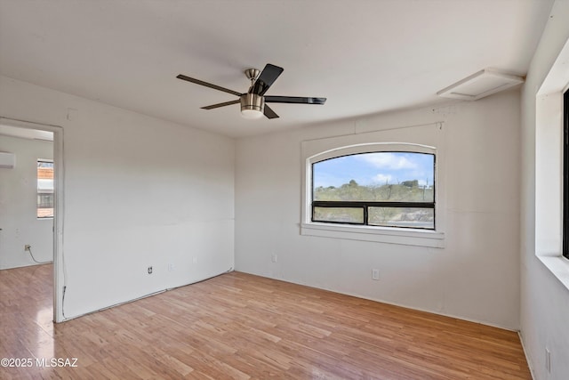 empty room featuring ceiling fan, a wall mounted air conditioner, light hardwood / wood-style flooring, and a wealth of natural light