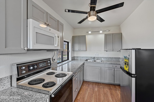 kitchen with electric range oven, stainless steel refrigerator, sink, gray cabinetry, and light hardwood / wood-style floors