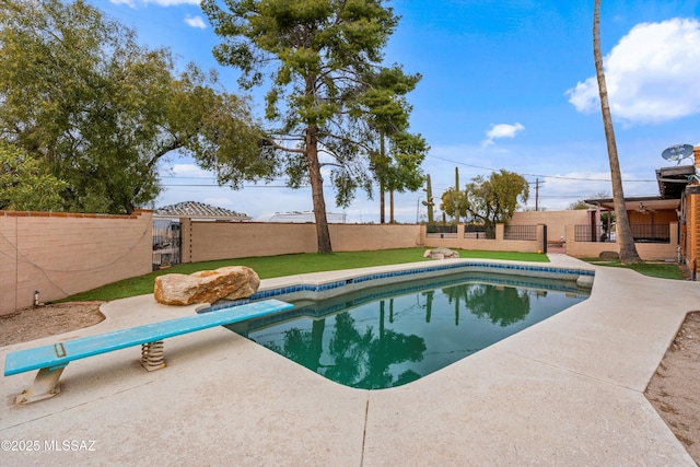 view of swimming pool featuring a diving board and a patio