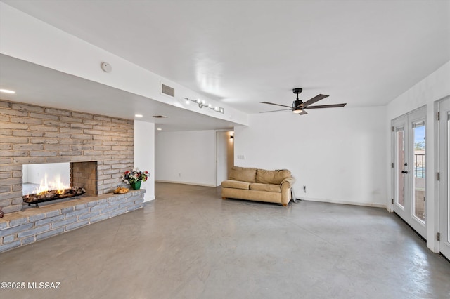 unfurnished living room with ceiling fan, concrete floors, and a fireplace