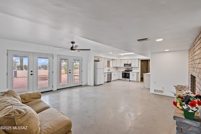 living room with french doors, ceiling fan, and a brick fireplace