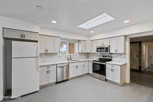 kitchen featuring stainless steel appliances, sink, backsplash, and a skylight