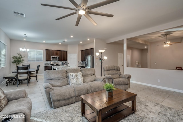 living room with light tile patterned floors and ceiling fan with notable chandelier