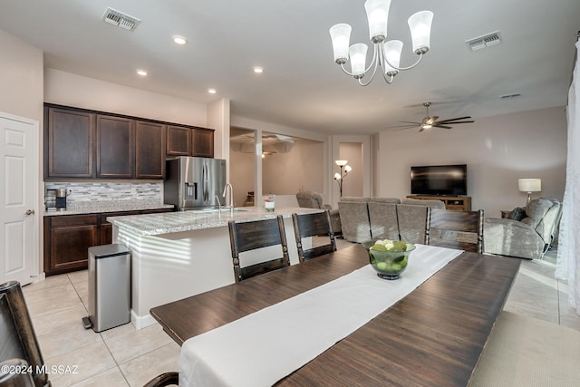 tiled dining area featuring sink and ceiling fan with notable chandelier