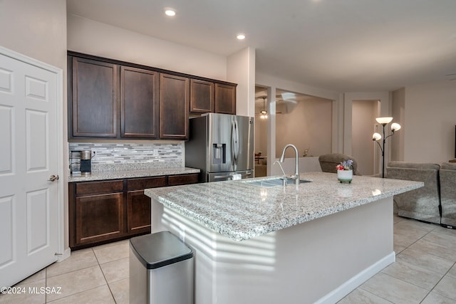 kitchen featuring dark brown cabinetry, sink, stainless steel fridge with ice dispenser, a kitchen island with sink, and backsplash