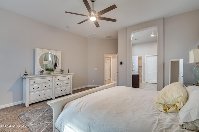 bedroom with connected bathroom, light colored carpet, and ceiling fan