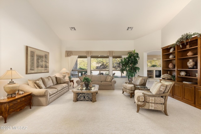 carpeted living area with high vaulted ceiling, arched walkways, and visible vents