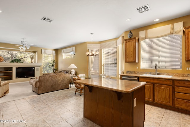 kitchen featuring sink, light tile patterned floors, hanging light fixtures, a kitchen breakfast bar, and a kitchen island