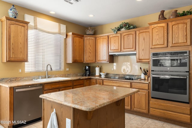 kitchen with sink, a center island, light tile patterned floors, stainless steel appliances, and light stone countertops