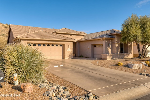 view of front facade with a garage, stucco siding, a tiled roof, and concrete driveway