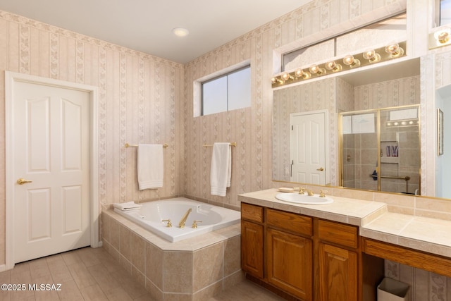 bathroom featuring wallpapered walls, vanity, a garden tub, and a stall shower