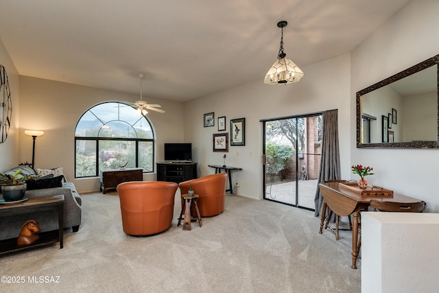 carpeted living room with ceiling fan with notable chandelier