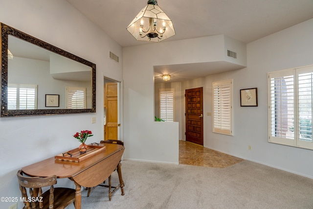 carpeted entryway featuring a healthy amount of sunlight and a chandelier