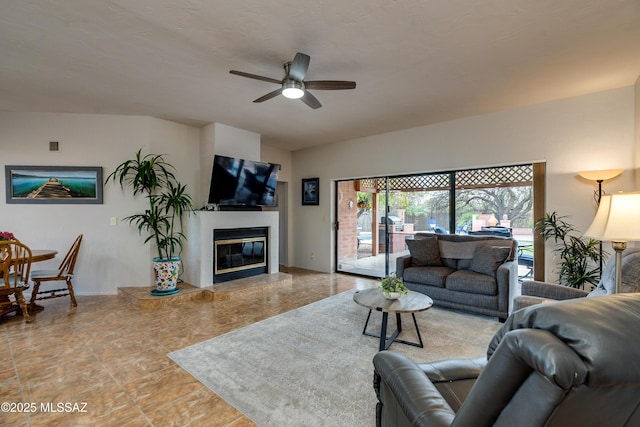 living room with a tile fireplace and ceiling fan