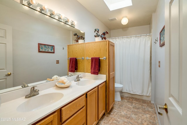 bathroom featuring vanity, toilet, and a skylight