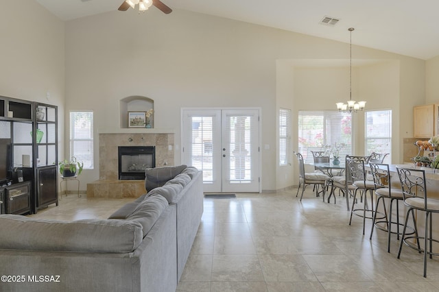 living room featuring a tiled fireplace, ceiling fan with notable chandelier, high vaulted ceiling, and light tile patterned floors