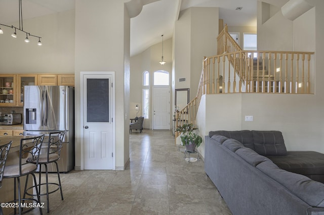 kitchen with stainless steel fridge, decorative light fixtures, and high vaulted ceiling