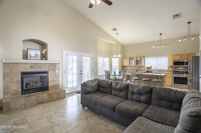 living room with sink, ceiling fan with notable chandelier, a fireplace, and high vaulted ceiling