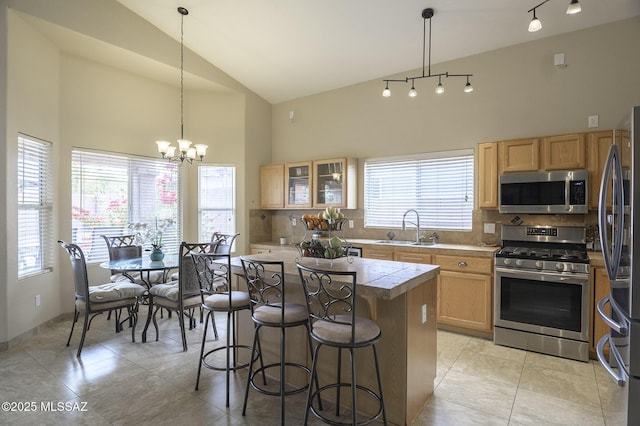 kitchen with appliances with stainless steel finishes, sink, backsplash, hanging light fixtures, and a center island