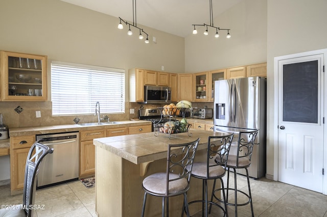 kitchen featuring a kitchen island, high vaulted ceiling, sink, hanging light fixtures, and stainless steel appliances