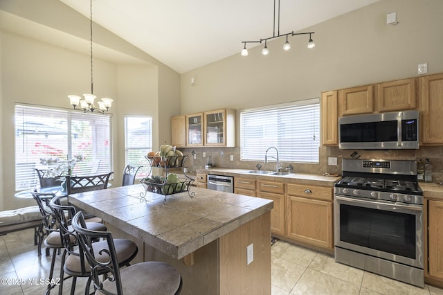 kitchen featuring pendant lighting, sink, appliances with stainless steel finishes, a center island, and tasteful backsplash