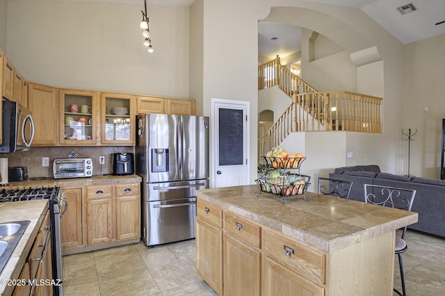 kitchen featuring a kitchen bar, tasteful backsplash, high vaulted ceiling, a kitchen island, and stainless steel appliances