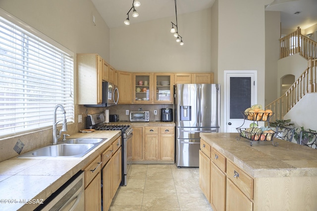 kitchen with sink, high vaulted ceiling, light tile patterned floors, appliances with stainless steel finishes, and pendant lighting