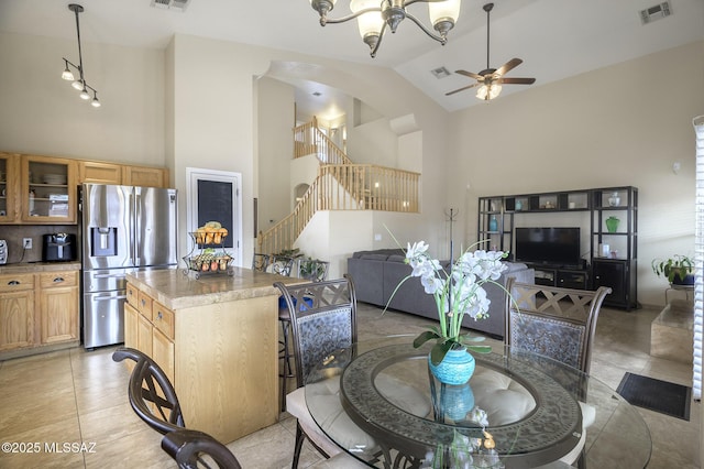 tiled dining space featuring ceiling fan with notable chandelier and high vaulted ceiling