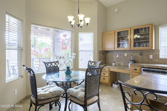 dining space featuring a high ceiling, a wealth of natural light, light tile patterned floors, and built in desk