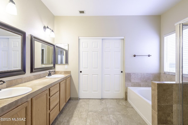 bathroom with tile patterned flooring, a bathing tub, and vanity