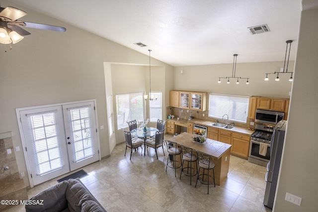 kitchen featuring sink, a breakfast bar area, decorative light fixtures, appliances with stainless steel finishes, and a kitchen island