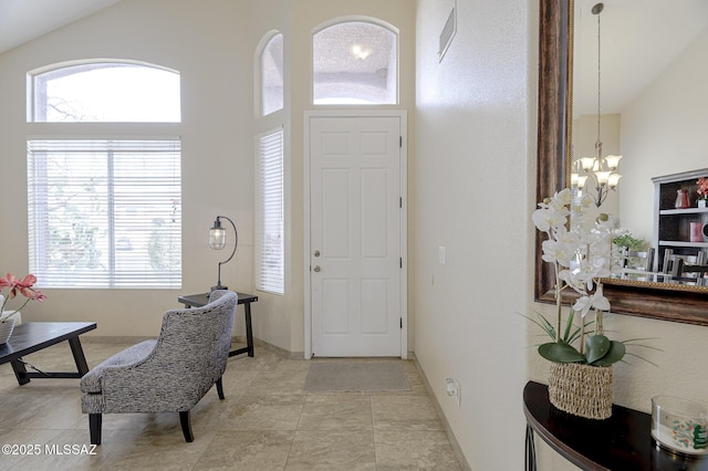 entrance foyer with light tile patterned floors, a healthy amount of sunlight, high vaulted ceiling, and a notable chandelier